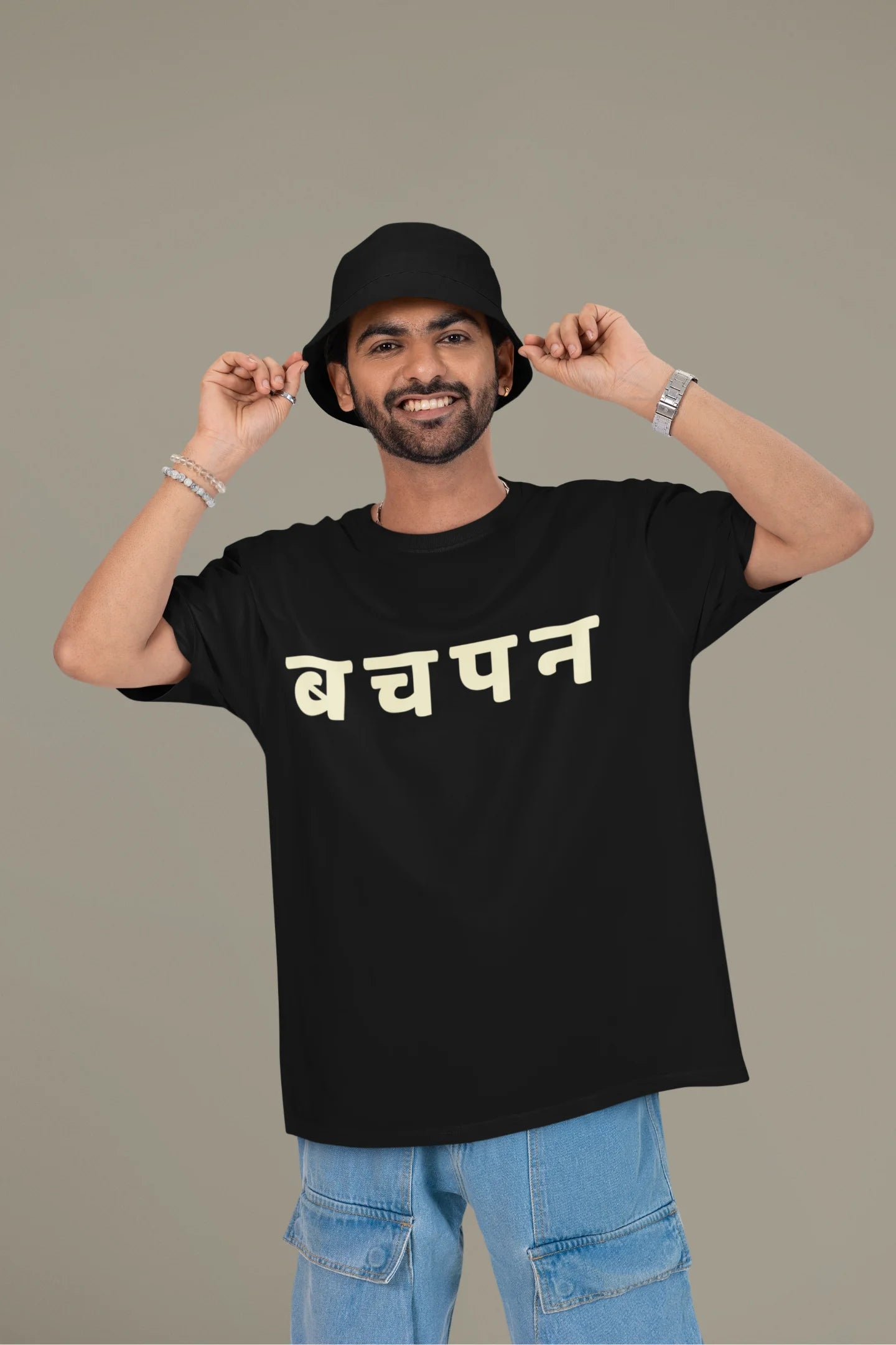 First front view of a male model wearing a black oversized t-shirt featuring a collage of illustrations or symbols representing various childhood games commonly played by kids in India.