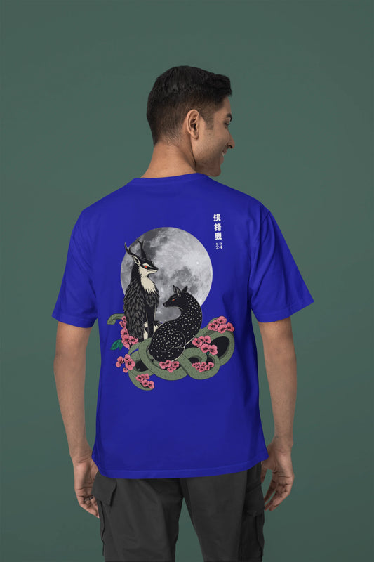 Back view of a male model wearing an oversized royal blue t-shirt featuring a detailed illustration of a gray wolf howling at a full moon in a nighttime setting.