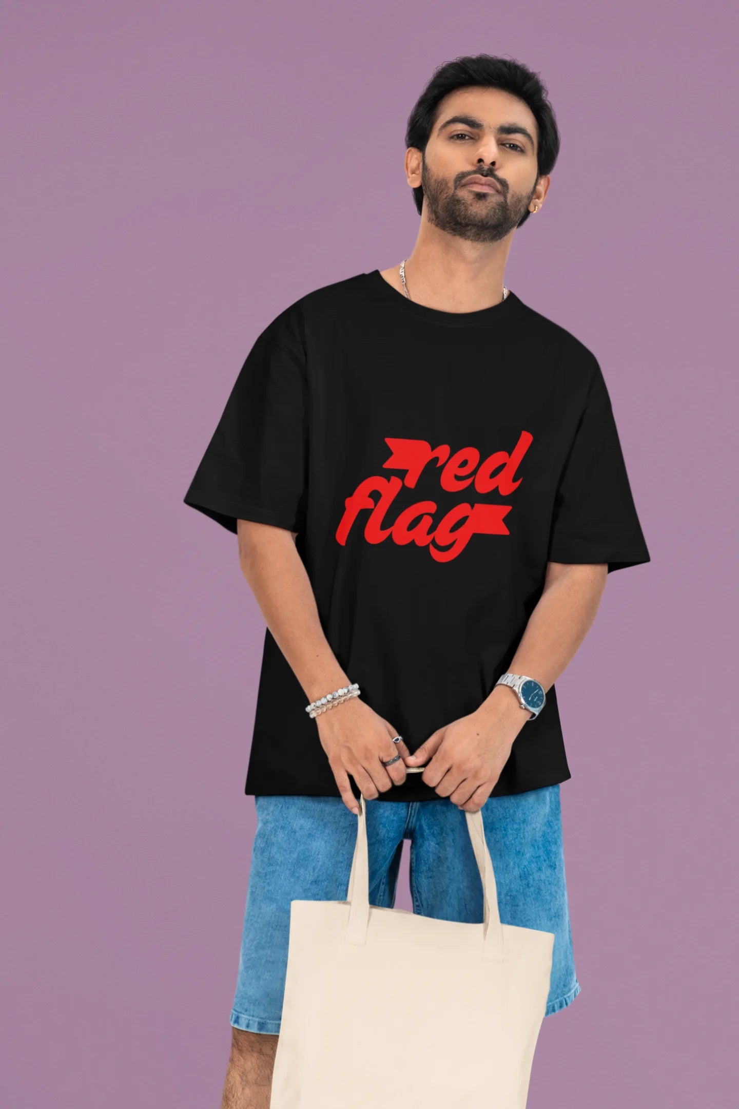 3rd front view of a male model wearing an black oversized t-shirt with the text "Red Flag" printed on it.