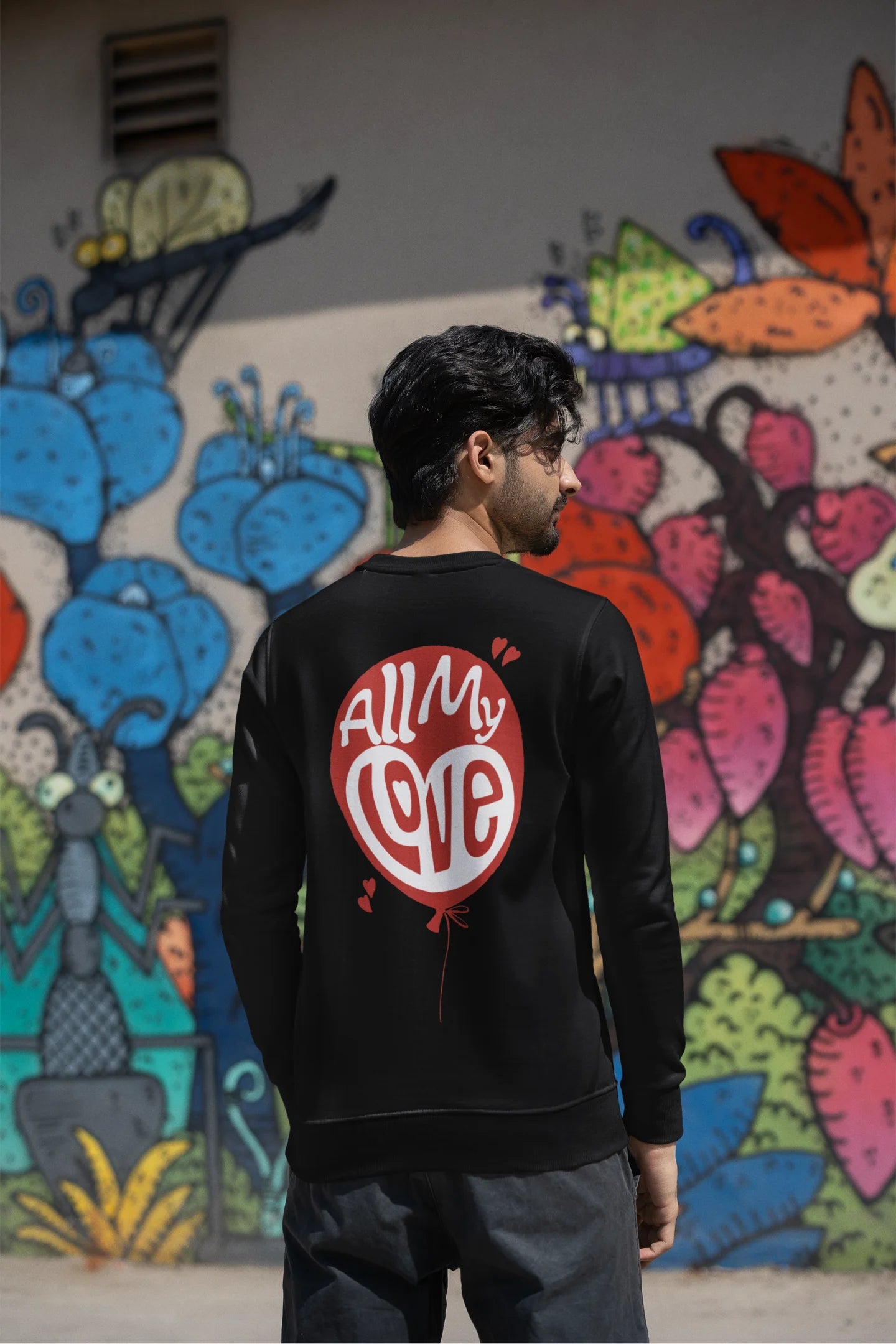 Back view of a male model wearing a black sweatshirt with a heart design and the text "All My Love".