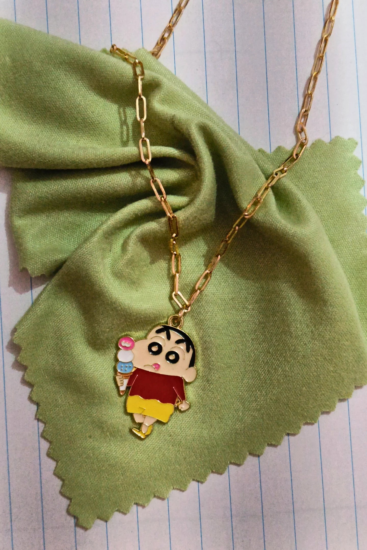 First view of a gold chain necklace with a small pendant depicting Shin Chan eating ice cream.