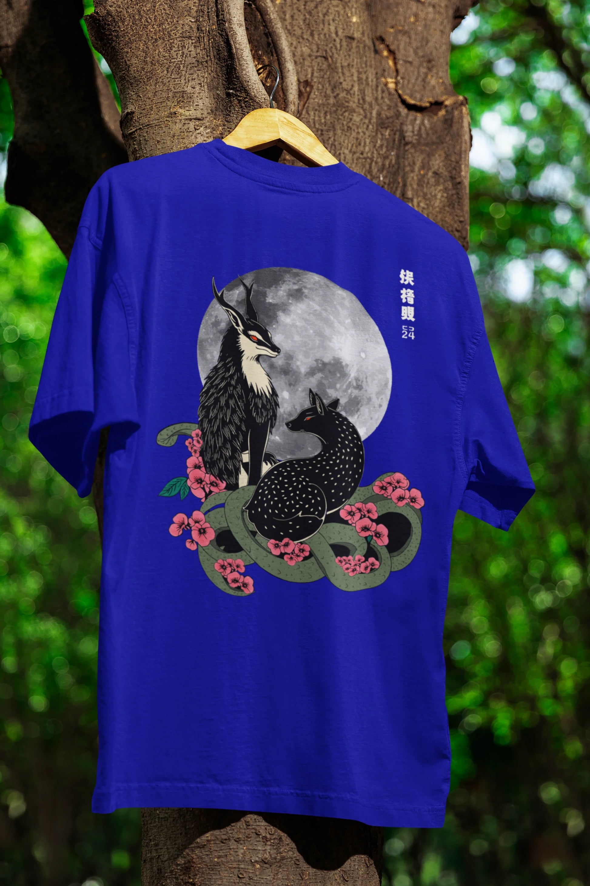 An oversized royal blue t-shirt featuring a detailed illustration of a gray wolf howling at a full moon in a nighttime setting.