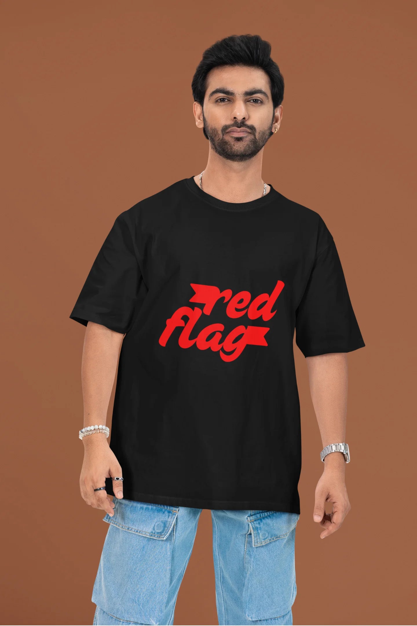 First front view of a male model wearing an black oversized t-shirt with the text "Red Flag" printed on it.