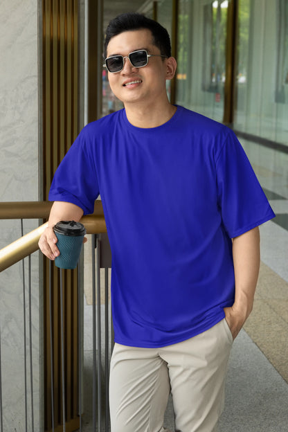 Front view of a male model wearing a royal blue oversized tee with a design of a cat dressed as a samurai, standing against a backdrop of waves and a rising sun.