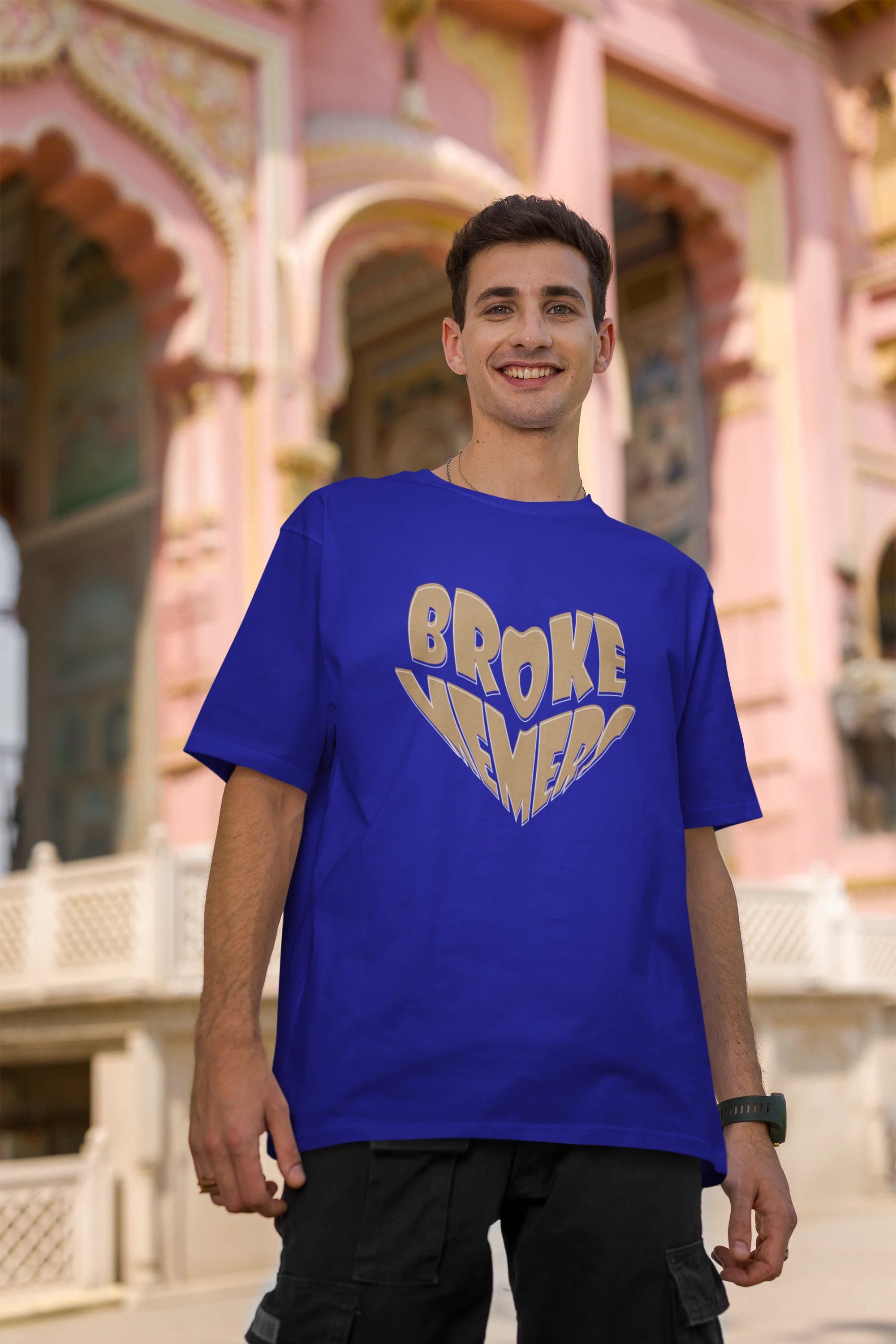 Second front view of male model wearing a royal blue oversized t-shirt featuring the "Broke Memers" logo creatively shaped like a heart. Ideal for fans of Broke Memers who love quality and fashionable clothing.