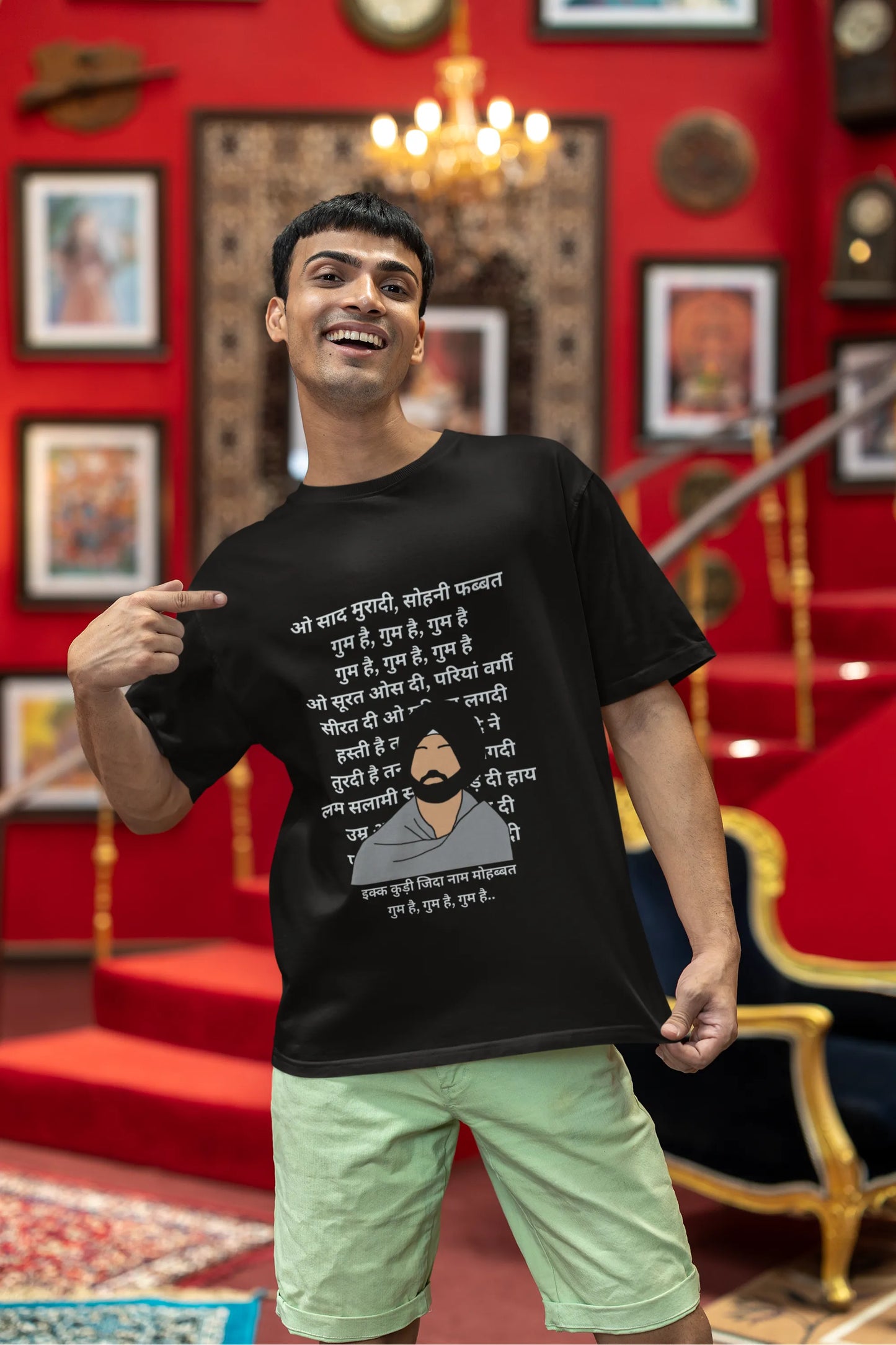 Third front view of a male model wearing a black oversized  T-shirt with a Diljit Dosanjh portrait  with lyrics from the song "Ikk Kudi" in the background.