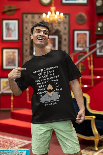 Third front view of a male model wearing a black oversized  T-shirt with a Diljit Dosanjh portrait  with lyrics from the song "Ikk Kudi" in the background.