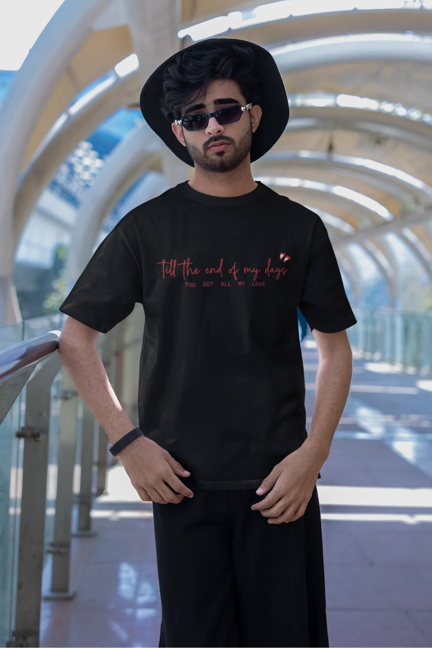 First front view of a male model wearing a black oversized t-shirt with a heart design and the text "All My Love".