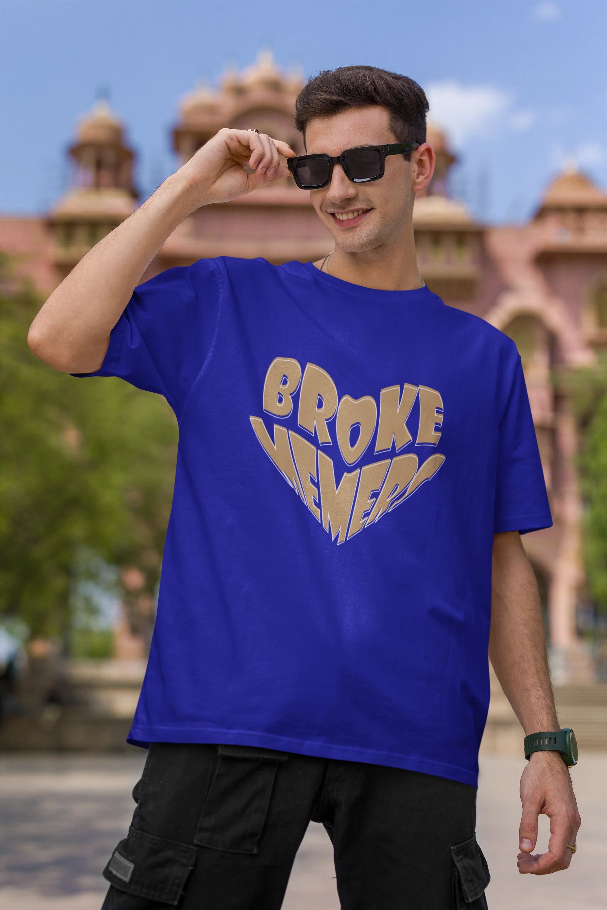 First front view of male model wearing a royal blue oversized t-shirt featuring the "Broke Memers" logo creatively shaped like a heart. Ideal for fans of Broke Memers who love quality and fashionable clothing.