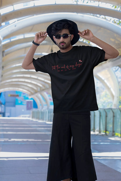 Second front view of a male model wearing a black oversized t-shirt with a heart design and the text "All My Love".
