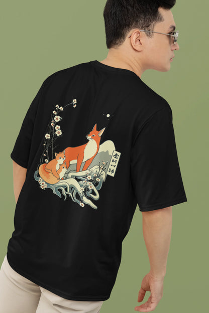 2nd back view of a male model wearing a black oversized tee with a design of a fox and its cub in a traditional Japanese landscape.