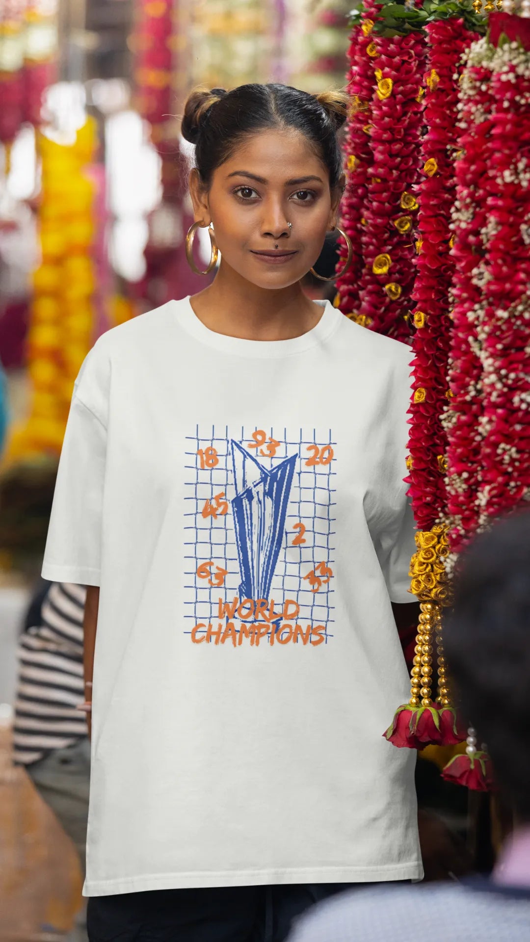 Third front image of female model wearing an off-white oversized t-shirt featuring the World Cup 2024 trophy with the text "World Champions" underneath. Ideal for Indian cricket fans celebrating their team's victory.