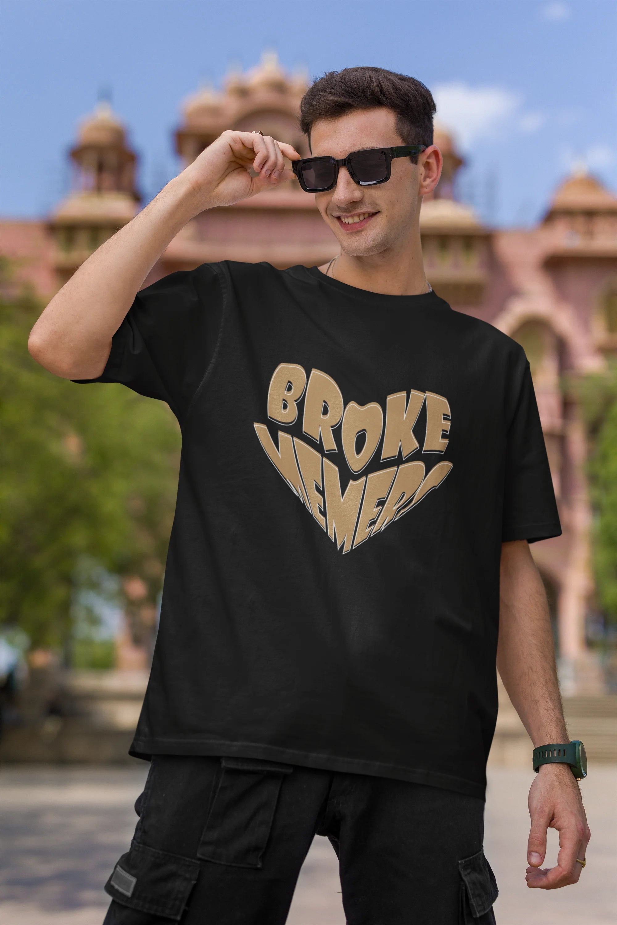 First front view of male model wearing a black oversized t-shirt featuring the "Broke Memers" logo creatively shaped like a heart. Ideal for fans of Broke Memers who love quality and fashionable clothing.