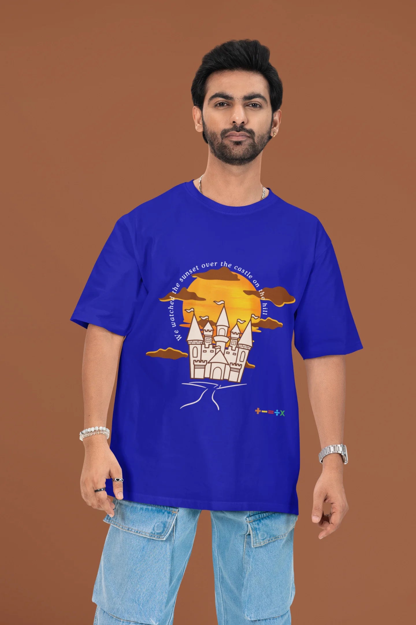 3rd front view of a male model wearing a royal blue oversized t-shirt featuring a nostalgic sunset and castle design, related to Ed Sheeran's "Castle on the Hill."