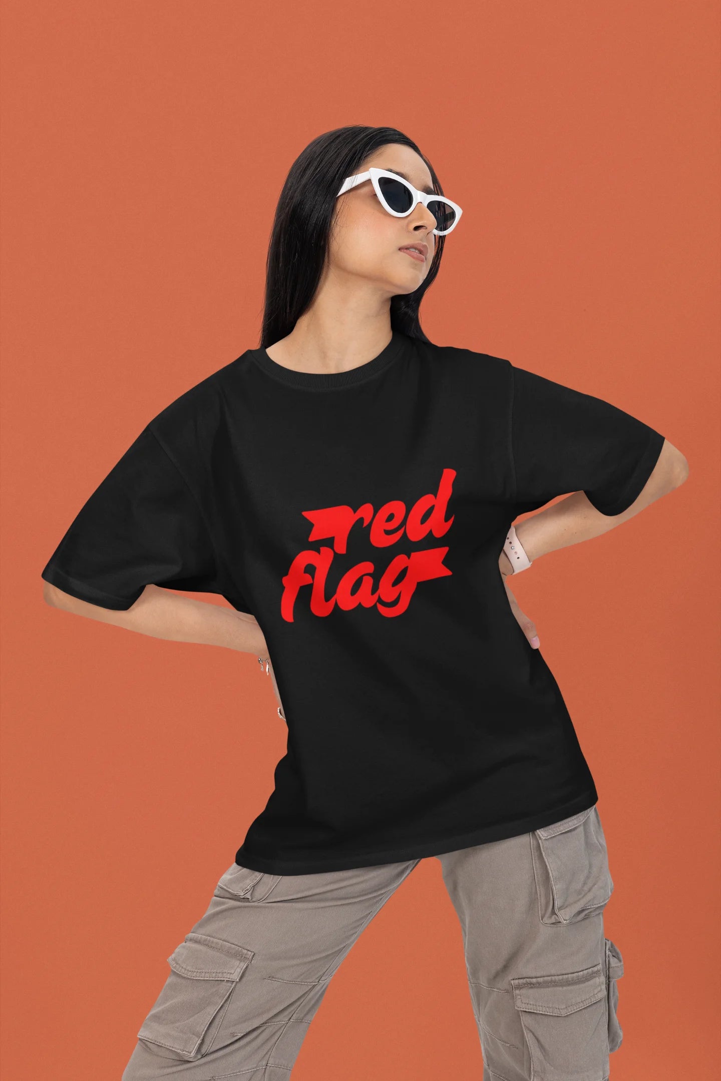 First front view of a female model wearing an black oversized t-shirt with the text "Red Flag" printed on it.