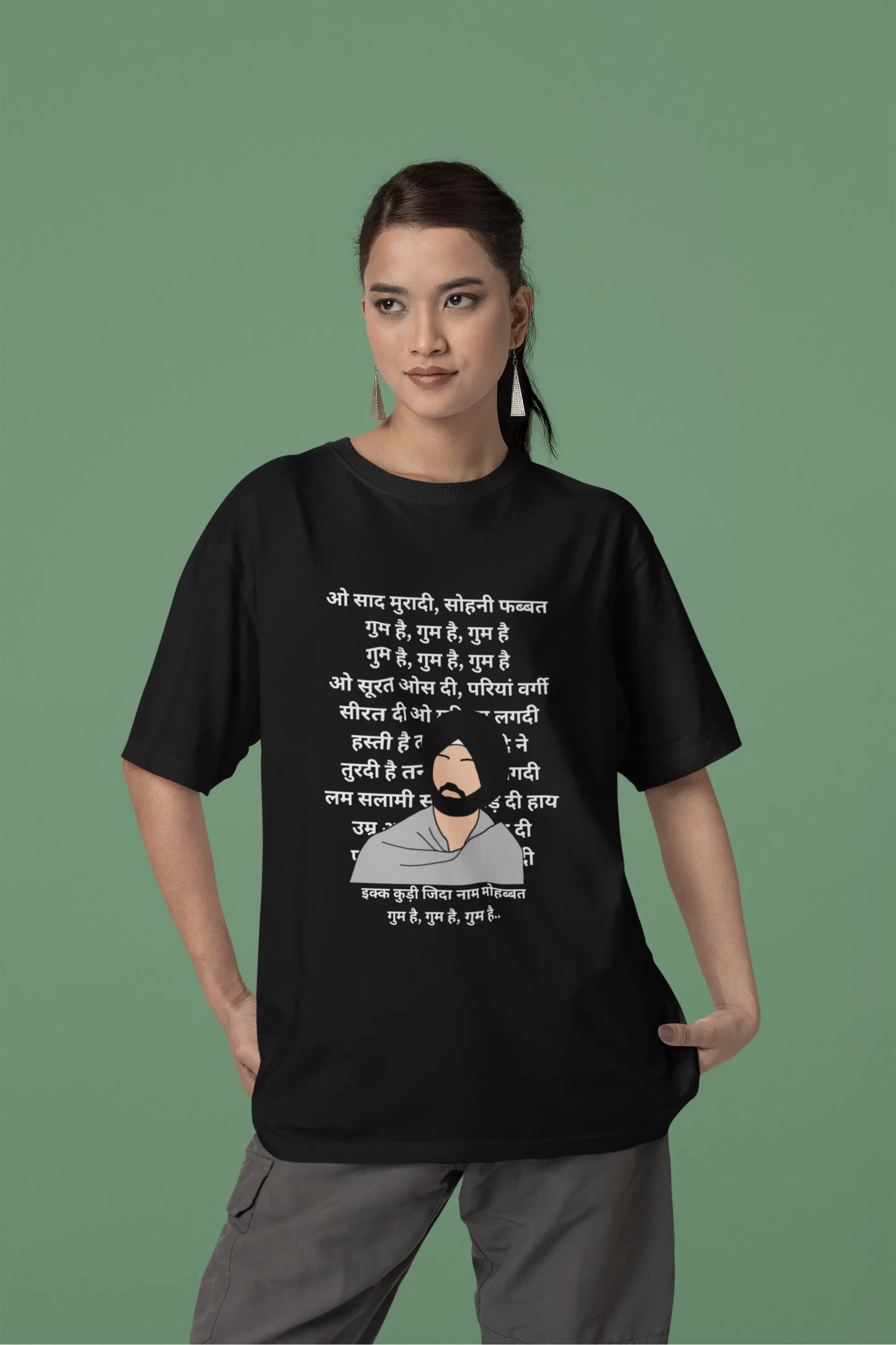 Second front view of a female model wearing a black oversized  T-shirt with a Diljit Dosanjh portrait  with lyrics from the song "Ikk Kudi" in the background.