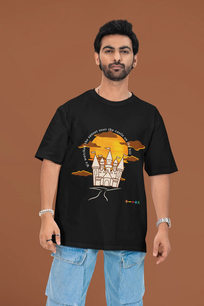 3rd front view of a male model wearing a black oversized t-shirt featuring a nostalgic sunset and castle design, related to Ed Sheeran's "Castle on the Hill."
