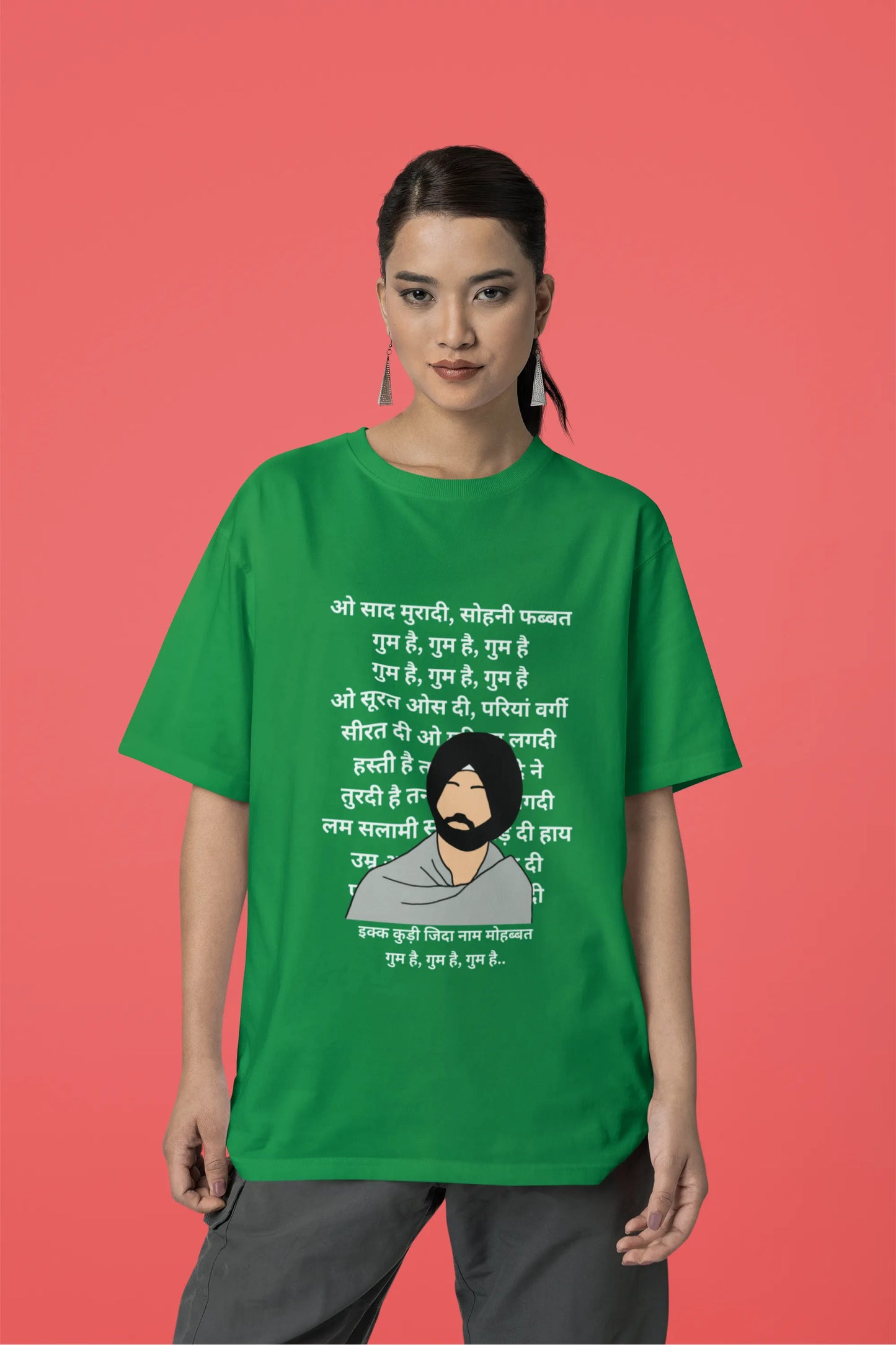 Third front view of a female model wearing a forest green oversized  T-shirt with a Diljit Dosanjh portrait  with lyrics from the song "Ikk Kudi" in the background.