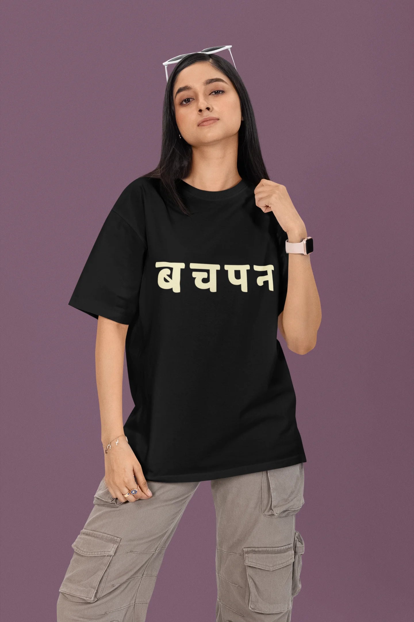 First front view of a female model wearing a black oversized t-shirt featuring a collage of illustrations or symbols representing various childhood games commonly played by kids in India.