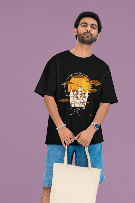 2nd front view of a male model wearing a black oversized t-shirt featuring a nostalgic sunset and castle design, related to Ed Sheeran's "Castle on the Hill."