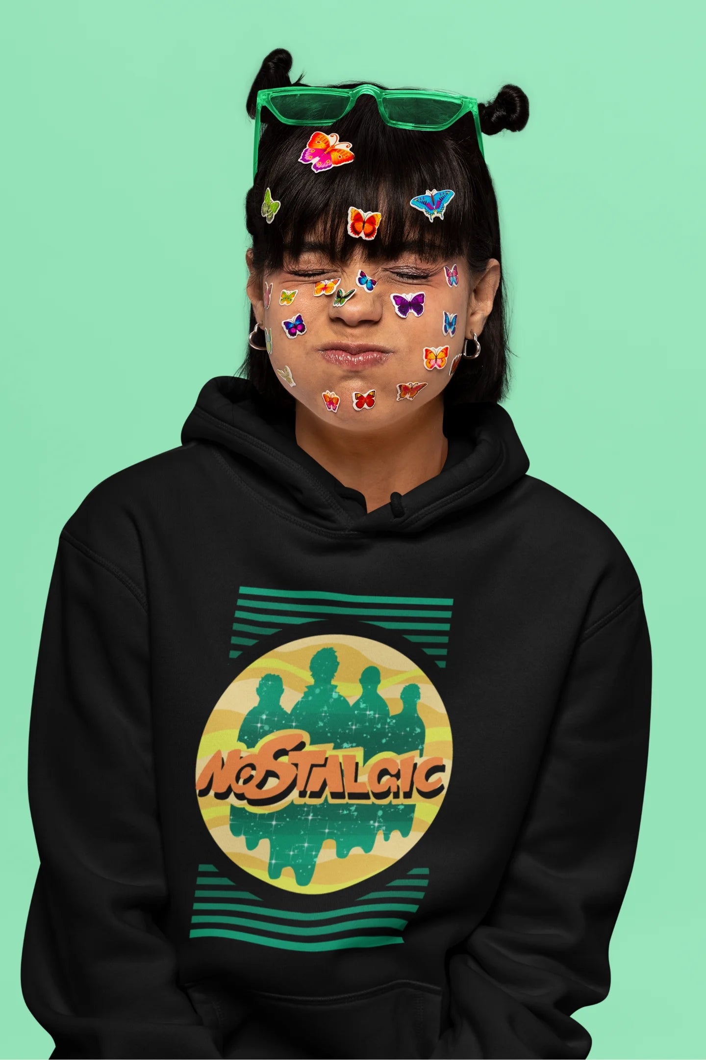 5th front view of a female model wearing an black hoodie with a shadow silhouette of the Coldplay band members and the word "Nostalgic" printed on it.