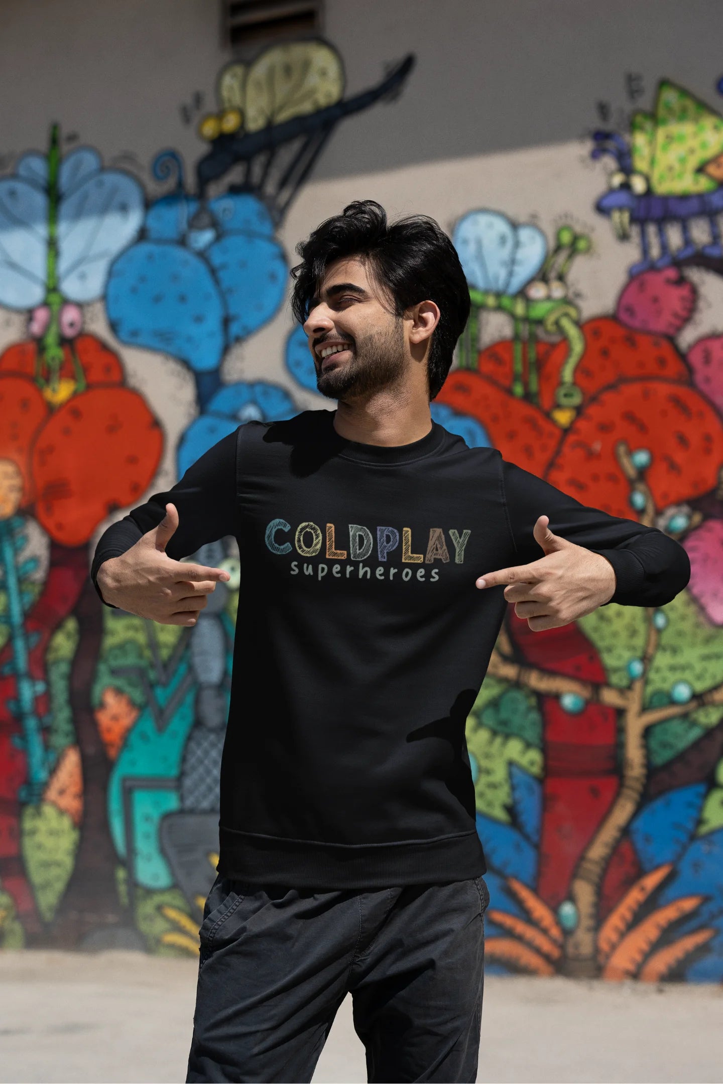 Third front view of a male model wearing an black sweatshirt with a design inspired by the "Something Just Like This" music video, featuring the word "Superheroes".
