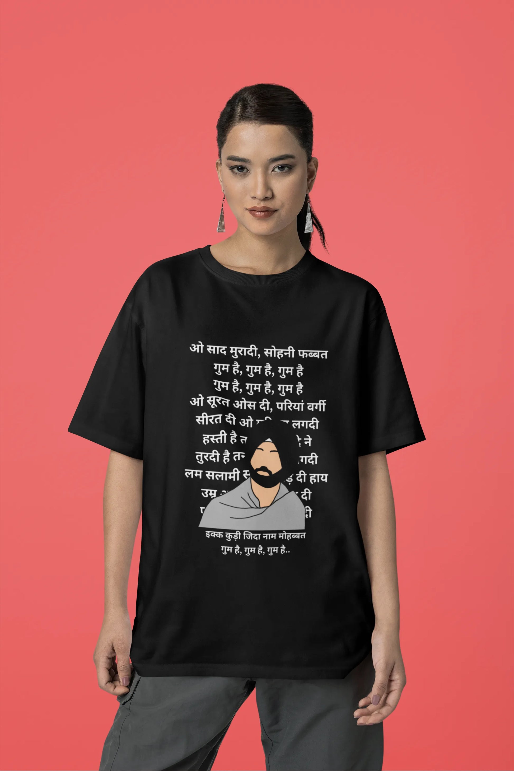 Third front view of a female model wearing a black oversized  T-shirt with a Diljit Dosanjh portrait  with lyrics from the song "Ikk Kudi" in the background.