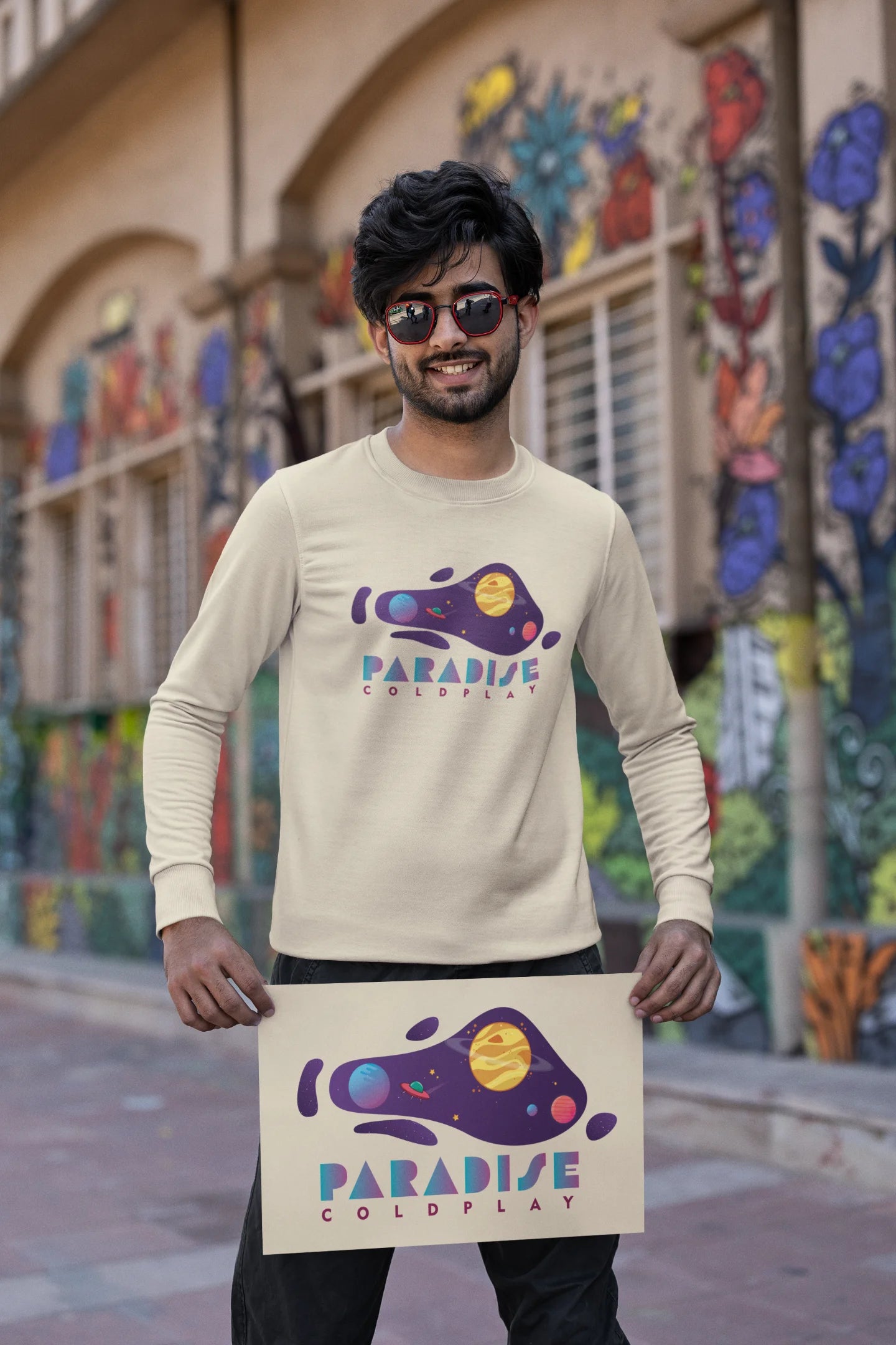 First front view of a male model wearing an cream sweatshirt with the "Paradise" album artwork by Coldplay.