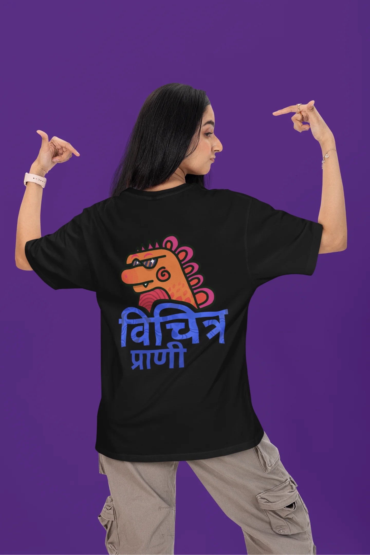 Back view of a female model wearing a black oversized tee with the phrase "Vichitra Pranee" (meaning "Strange being" or "alien") in a stylish Hindi font.