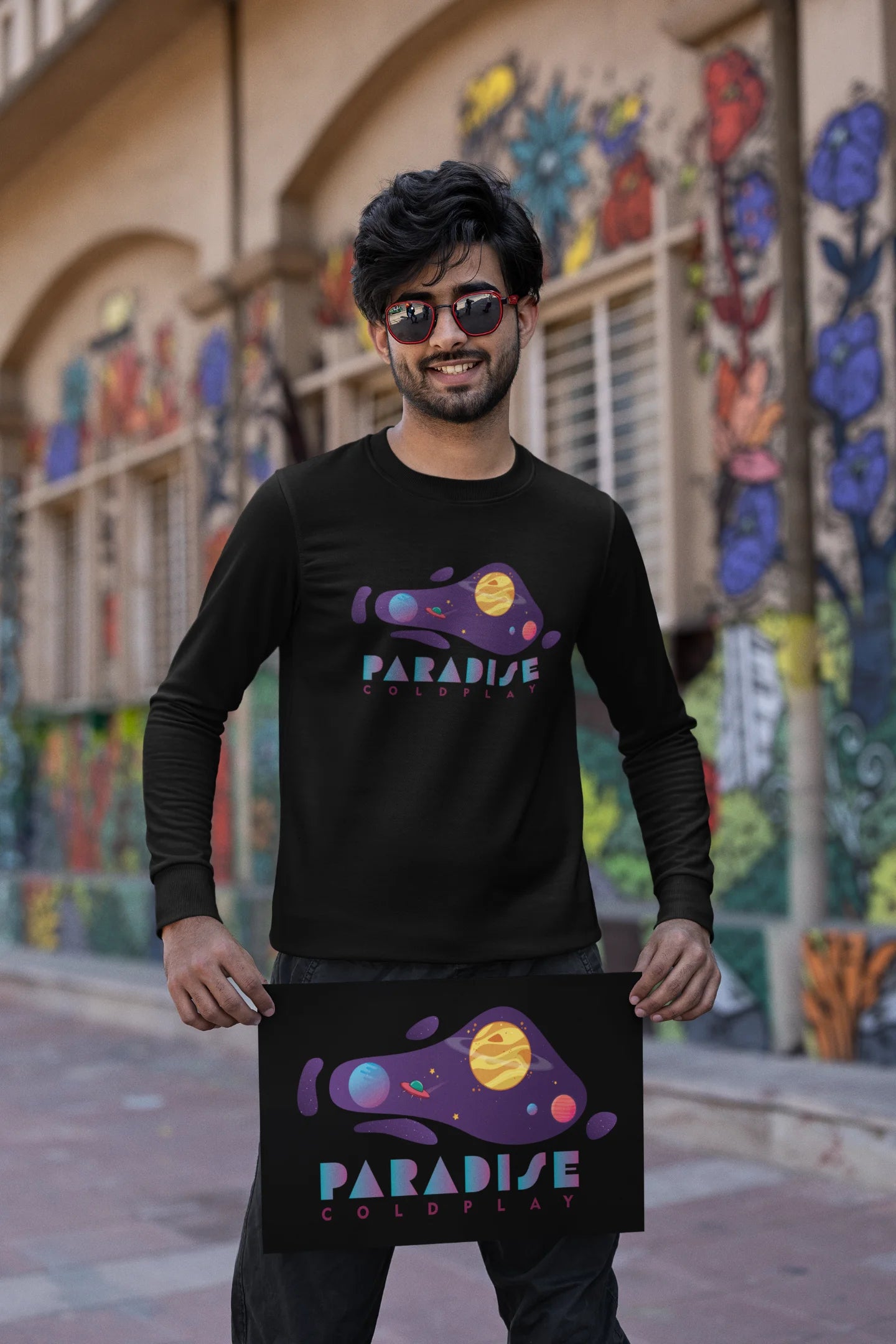 First front view of a male model wearing an black sweatshirt with the "Paradise" album artwork by Coldplay.