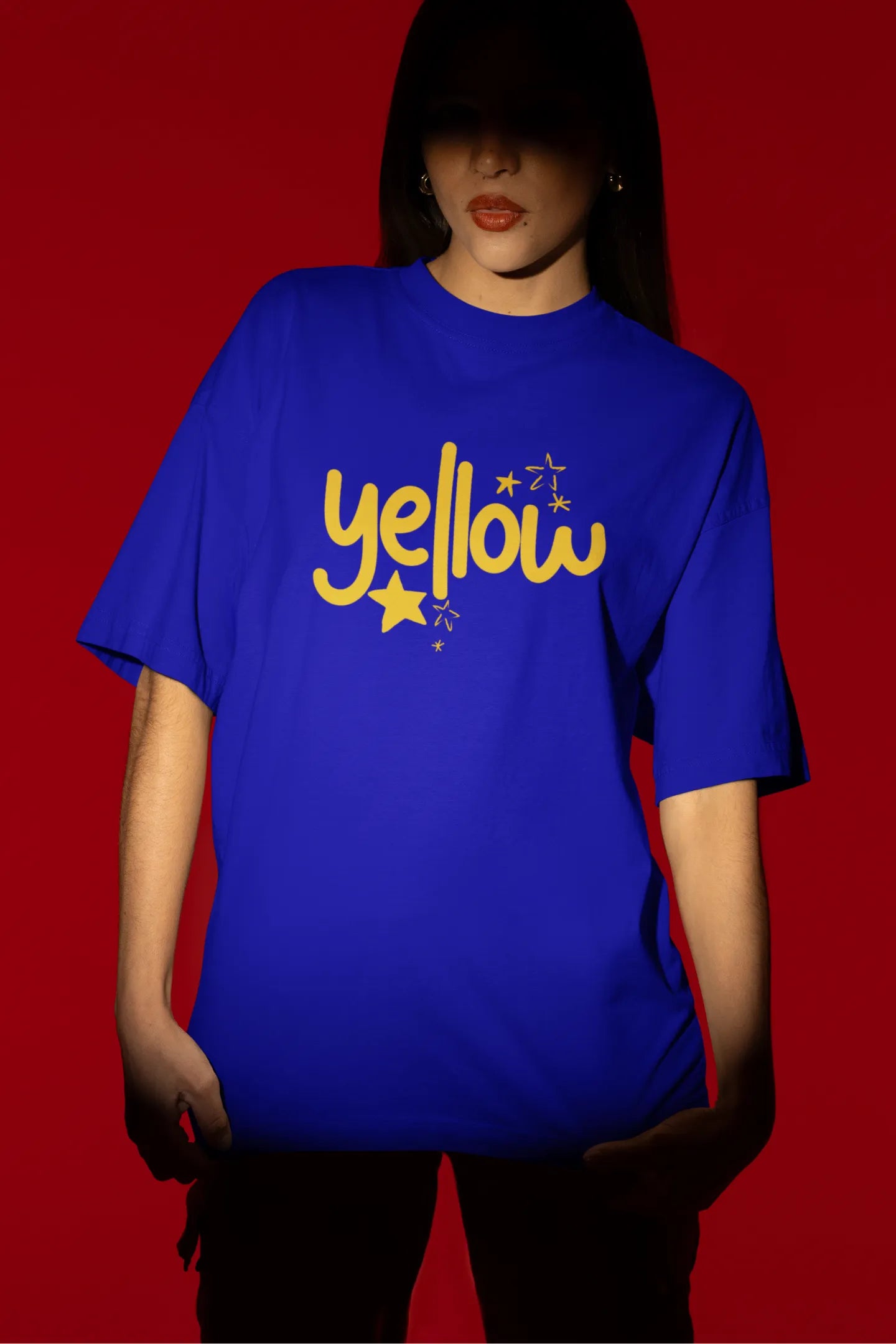 Second front view of a female model wearing a royal blue oversized t-shirt with the "Yellow" album artwork by Coldplay.