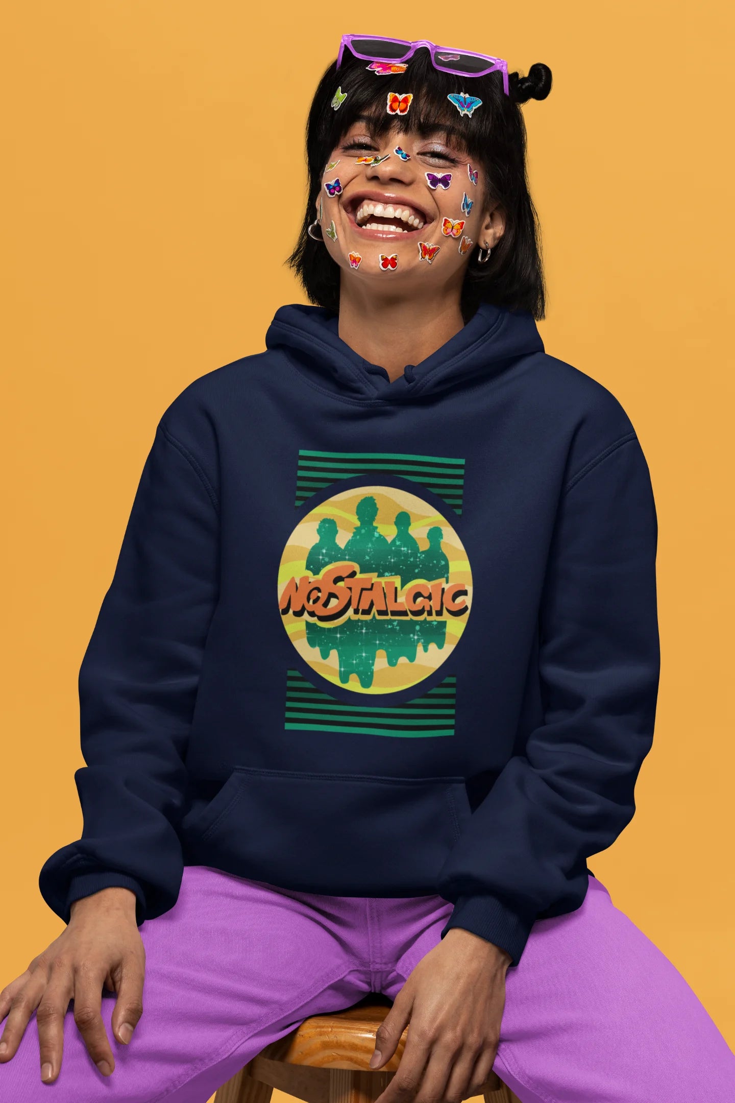 First front view of a female model wearing an navy blue hoodie with a shadow silhouette of the Coldplay band members and the word "Nostalgic" printed on it.