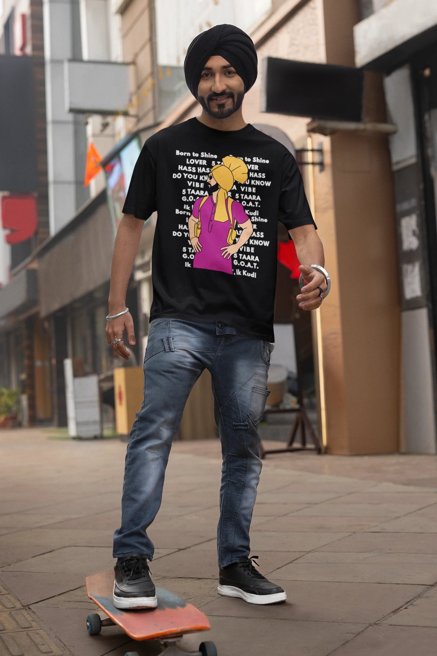 Third image of a male model wearing a black oversized t-shirt with a Diljit Dosanjh portrait on a t-shirt with his album titles written in the background.