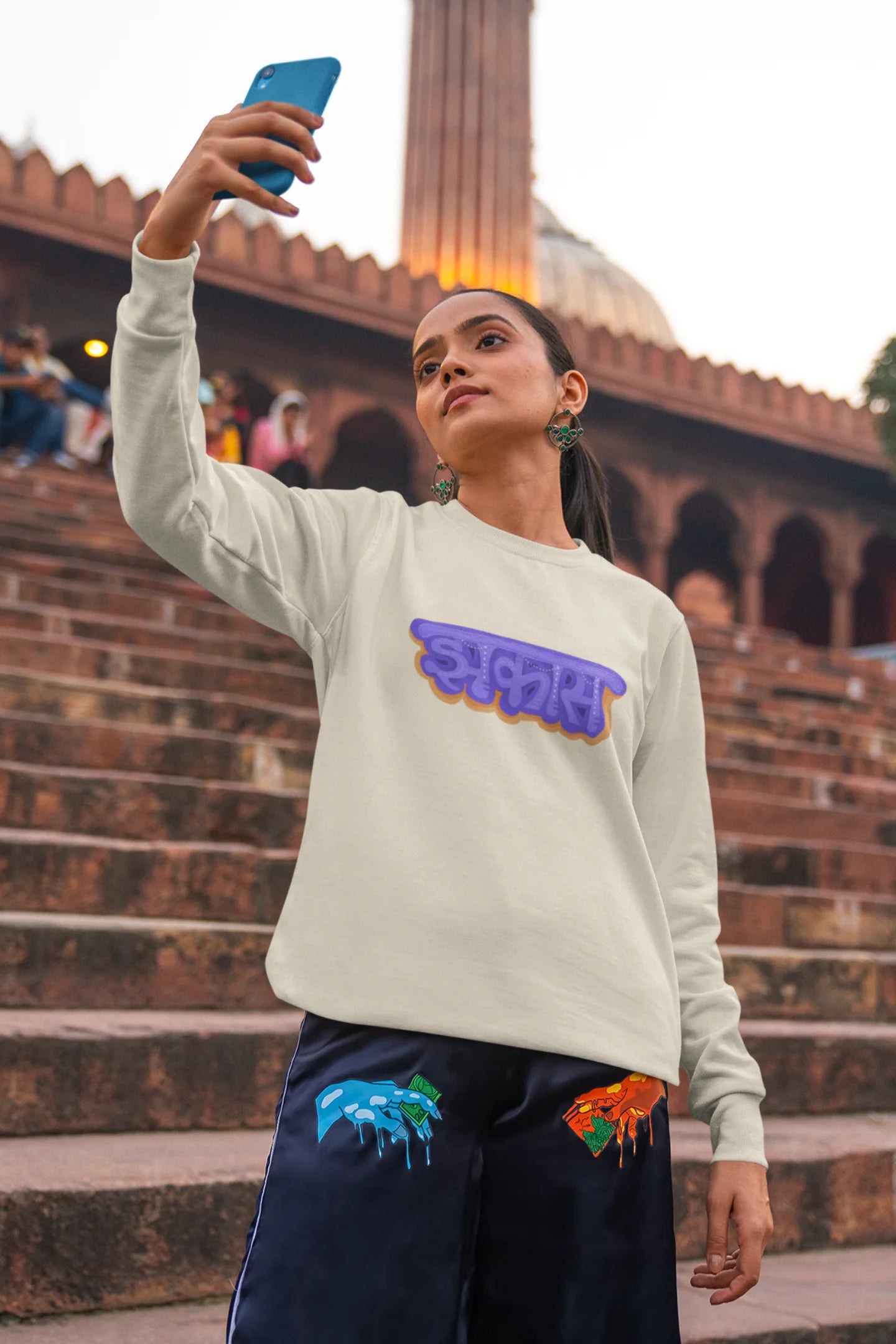 2nd front view of a female model wearing an cream sweatshirt featuring "Jhakas" in a stylish font.