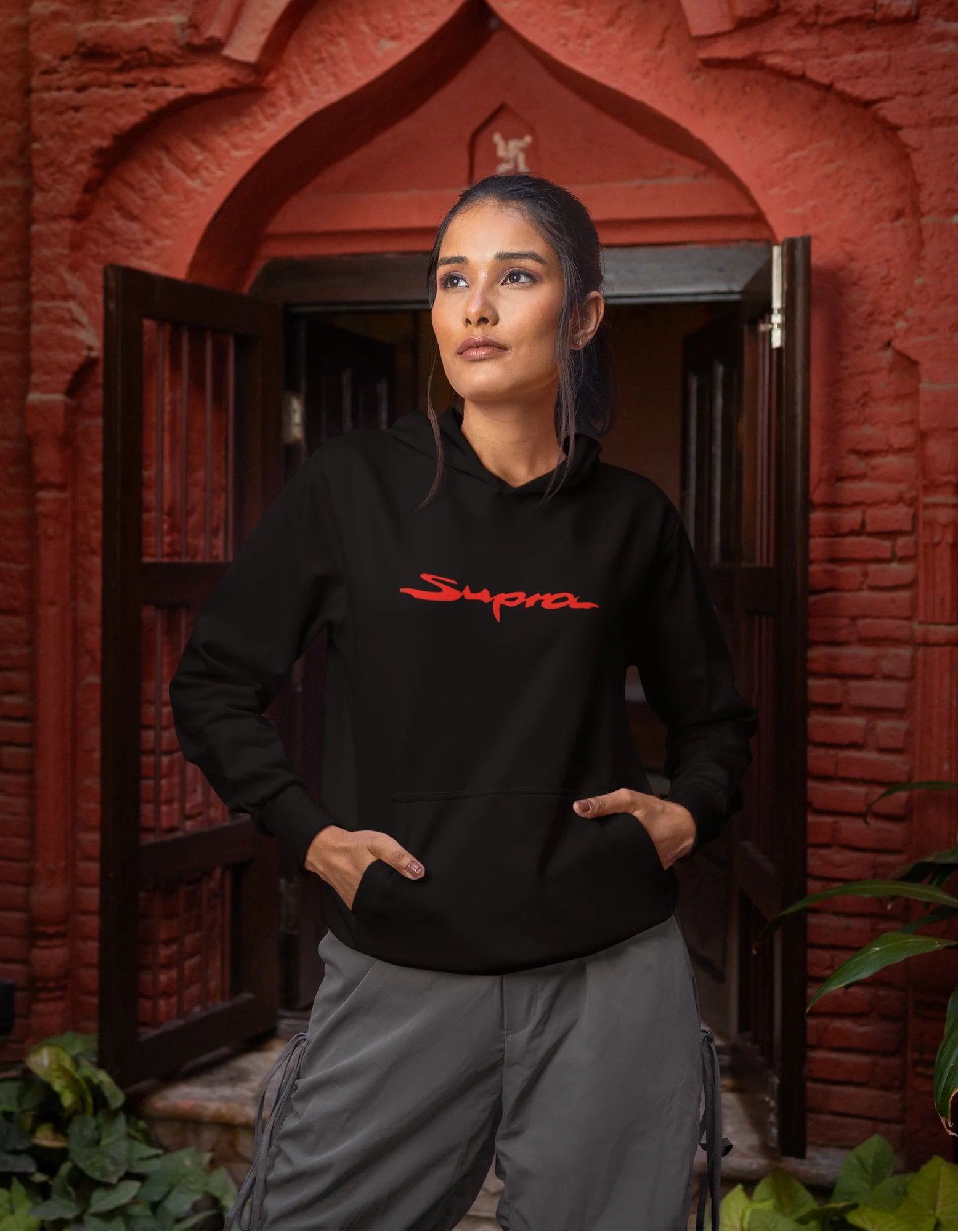 First front view of a female model wearing a black hoodie featuring a Toyota Supra design, exuding speed and power.