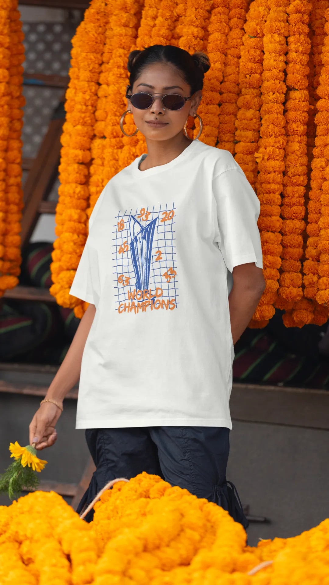 First front image of female model wearing an off-white oversized t-shirt featuring the World Cup 2024 trophy with the text "World Champions" underneath. Ideal for Indian cricket fans celebrating their team's victory.