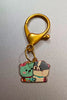 A couples keychain featuring two separate charms depicting cats hugging each other. The cats' colors may vary, including combinations of pink and black and white.