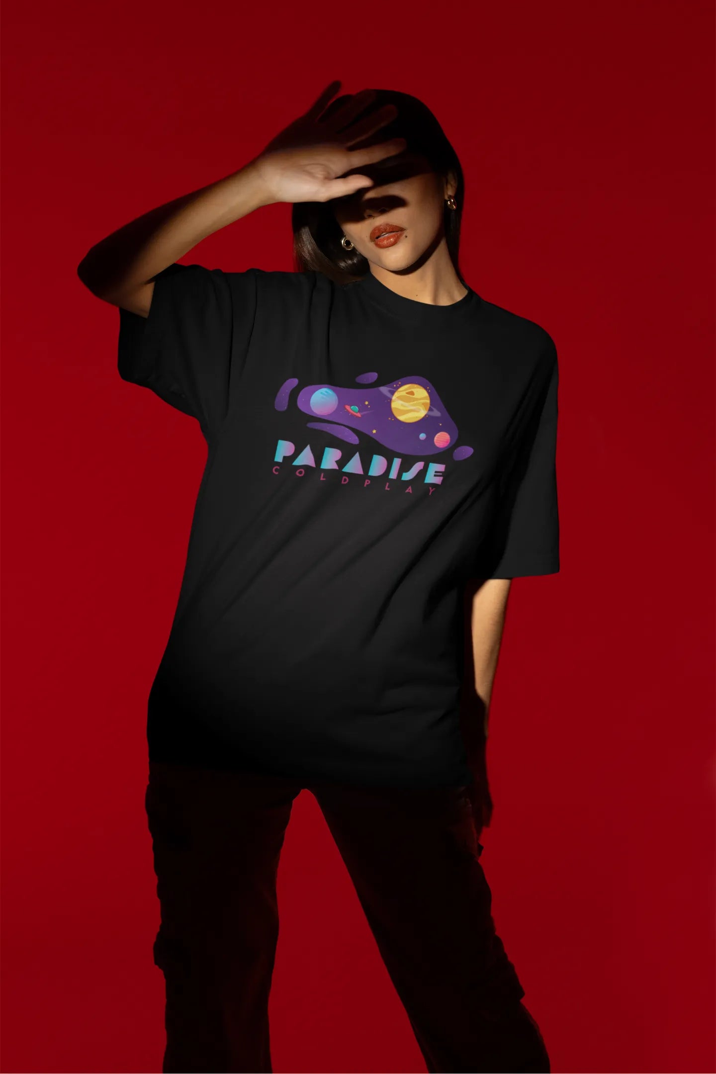 Third front view of a female model wearing an black oversized t-shirt with the "Paradise" album artwork by Coldplay.
