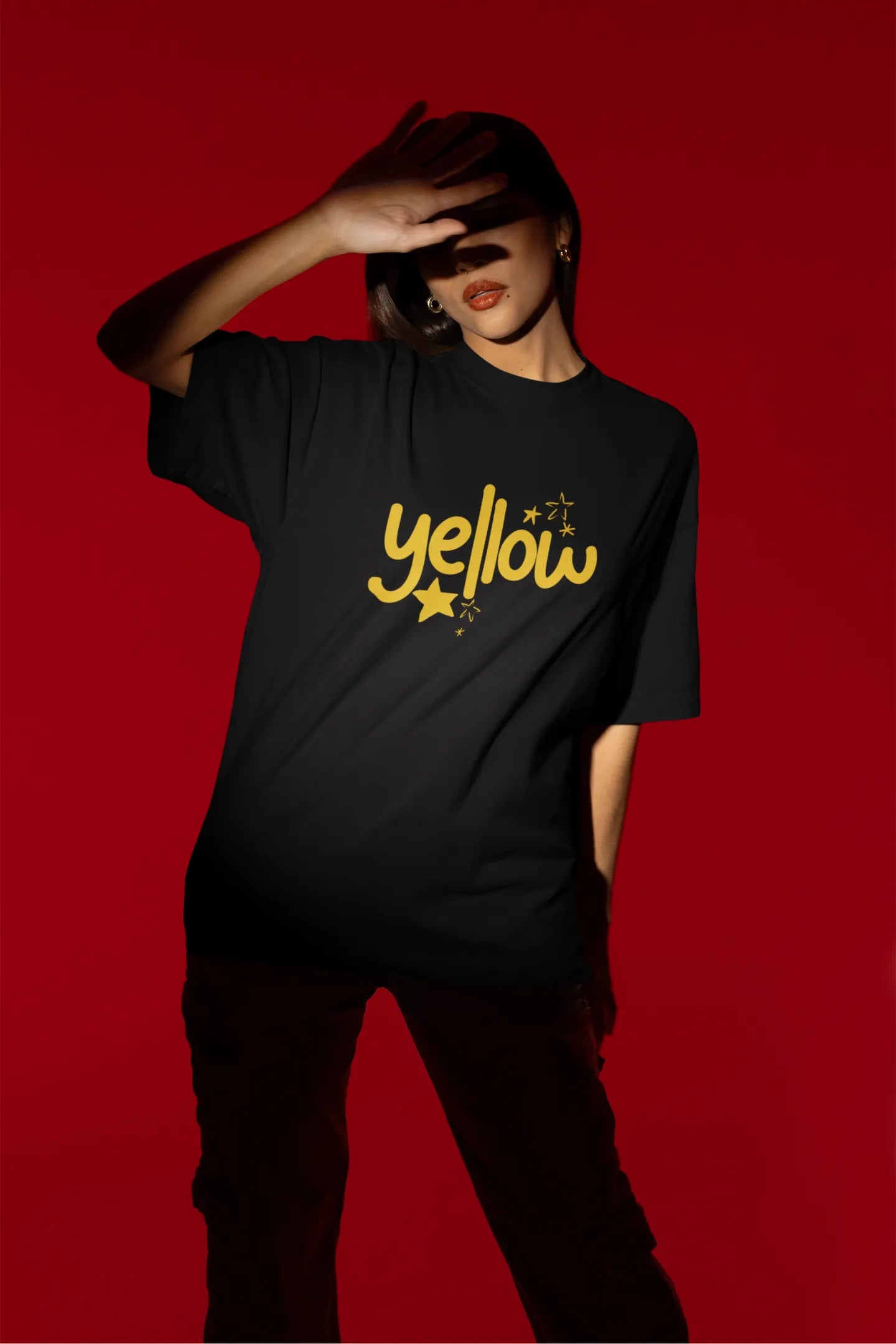 Third front view of a female model wearing a black oversized t-shirt with the "Yellow" album artwork by Coldplay.