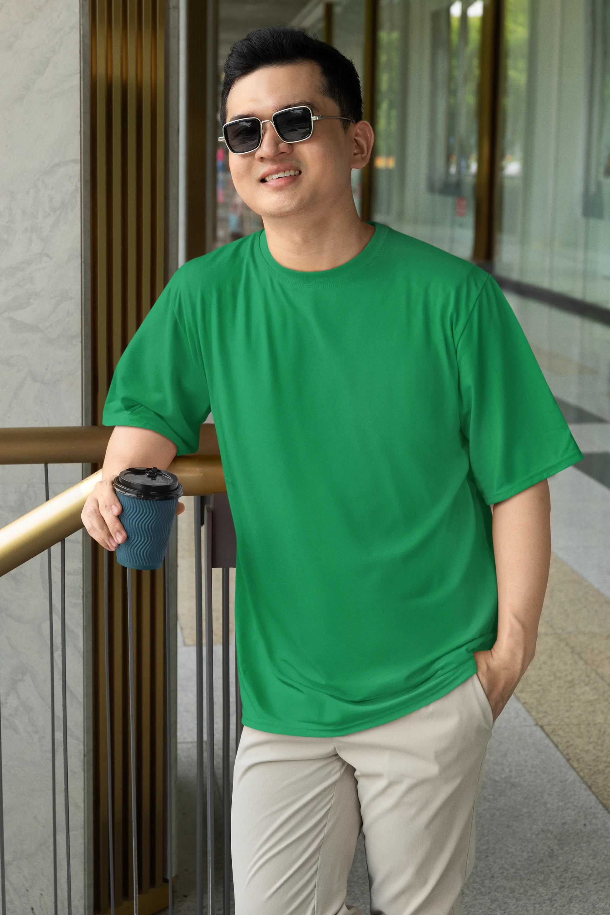 Front view of a male model wearing a forest green oversized tee with a design of a koi fish swimming in a bed of flowers.