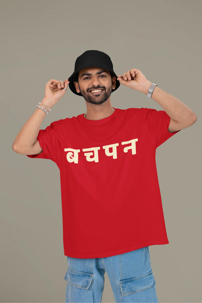 First front view of a male model wearing a red oversized t-shirt featuring a collage of illustrations or symbols representing various childhood games commonly played by kids in India.
