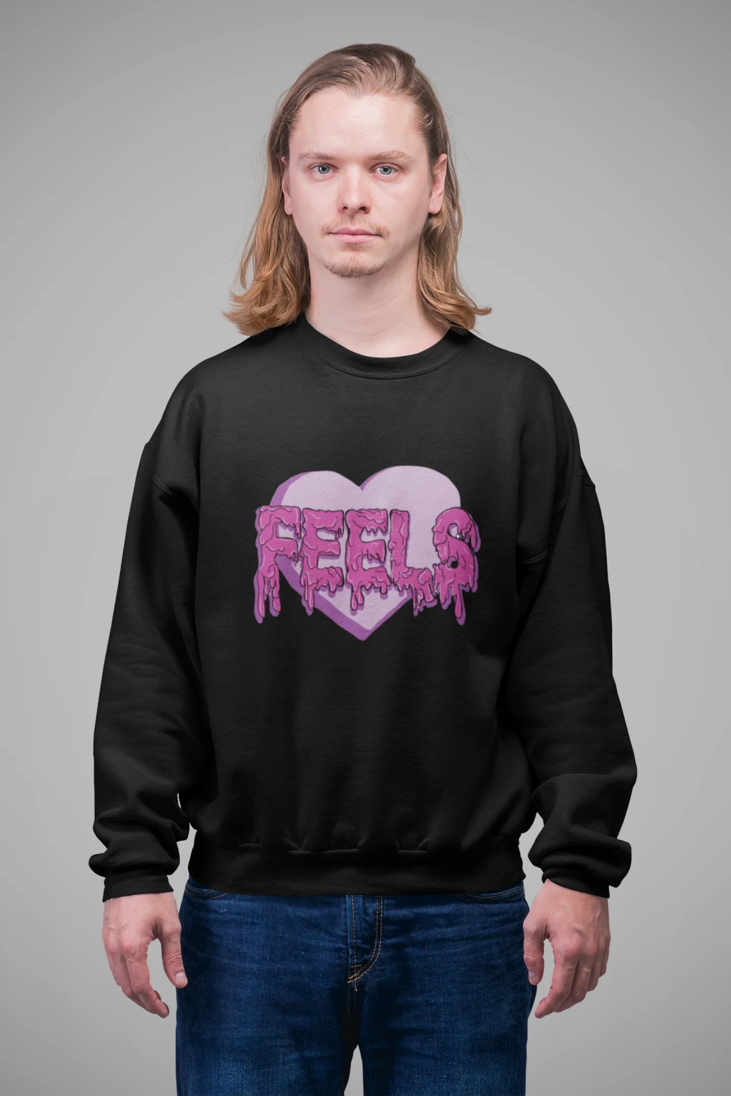 3rd front view of a male model wearing a black sweatshirt featuring a heart with melting "Feels" text.