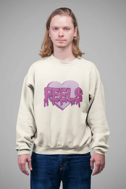 3rd front view of a male model wearing a cream sweatshirt featuring a heart with melting "Feels" text.