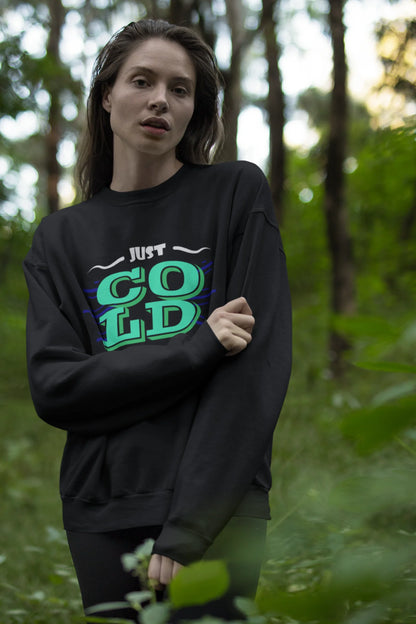 First front view of a female model wearing an black sweatshirt with the text "Just Cold" printed on it.