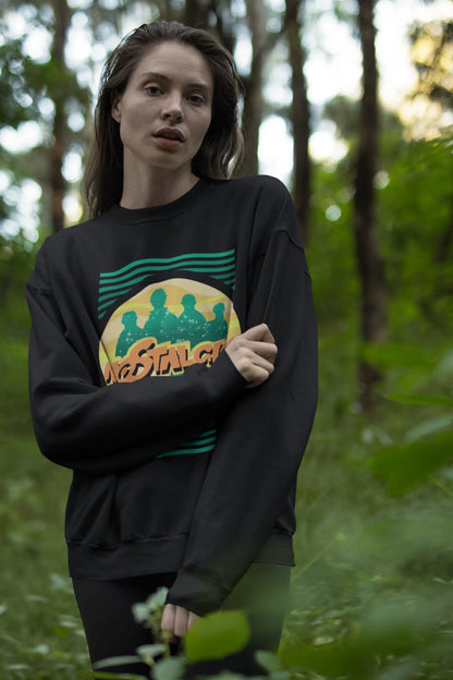 Third view of a female model wearing an oversized black sweatshirt with a shadow silhouette of the Coldplay band members and the word "Nostalgic" printed on it.
