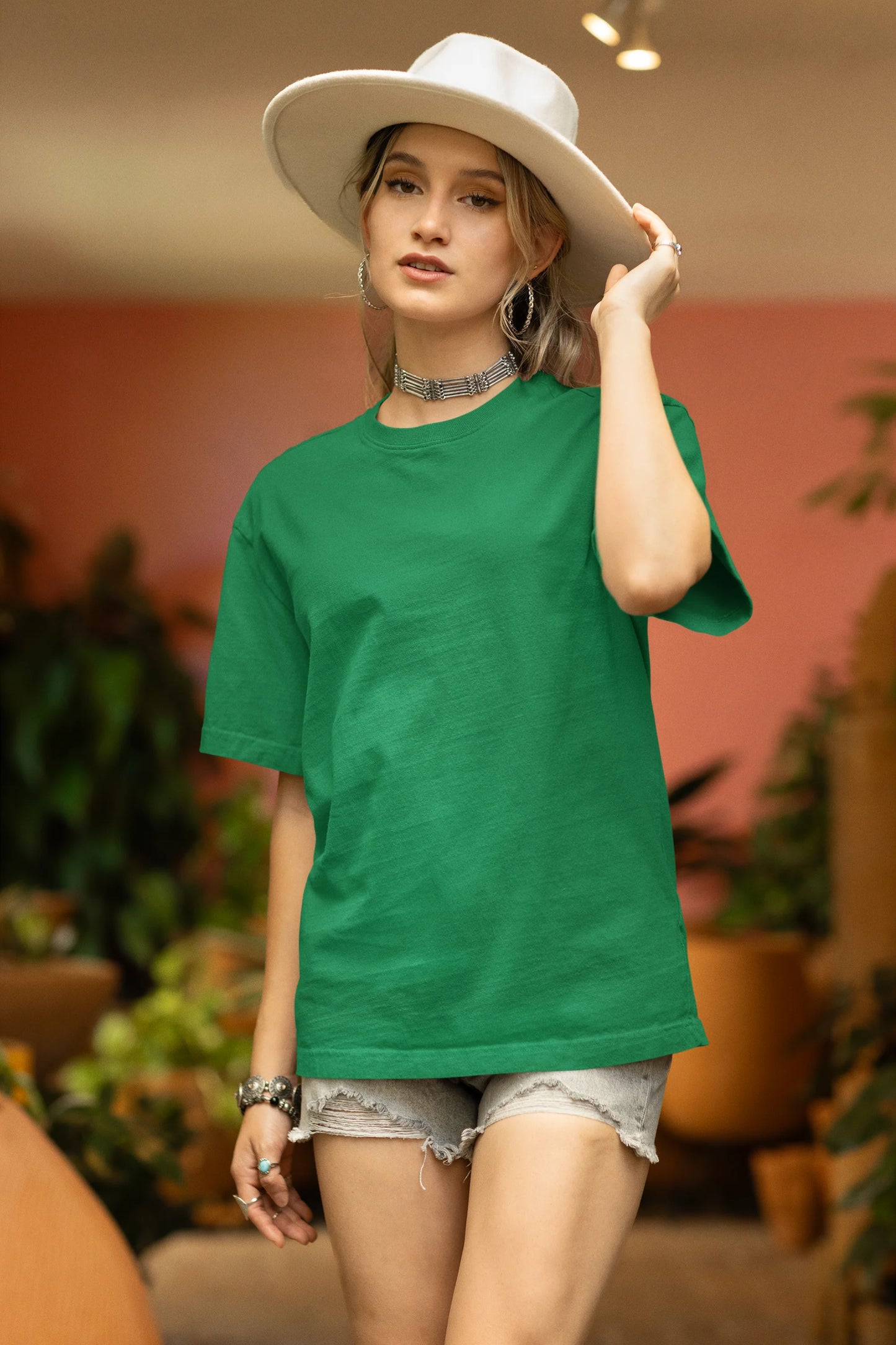Front view of a male model wearing a forest green oversized tee with a design of a koi fish swimming in a bed of flowers.
