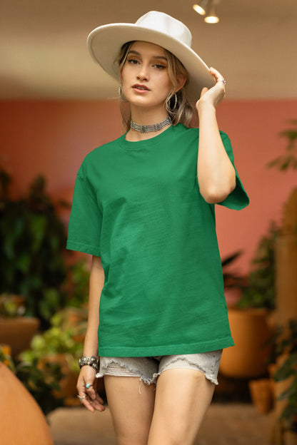 Front view of a male model wearing a forest green oversized tee with a design of a koi fish swimming in a bed of flowers.