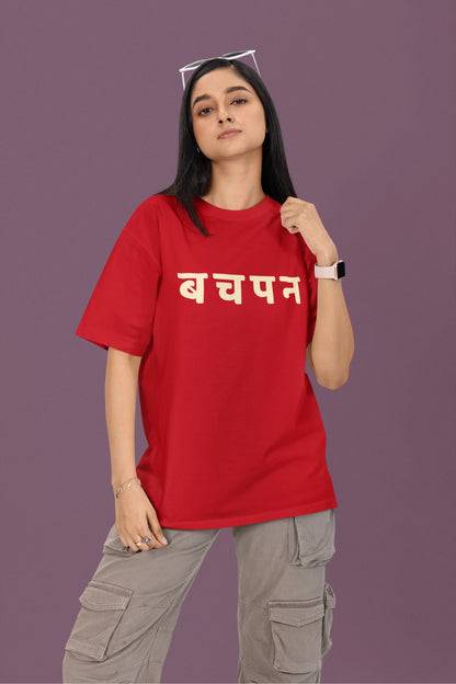 First front view of a female model wearing a red oversized t-shirt featuring a collage of illustrations or symbols representing various childhood games commonly played by kids in India.