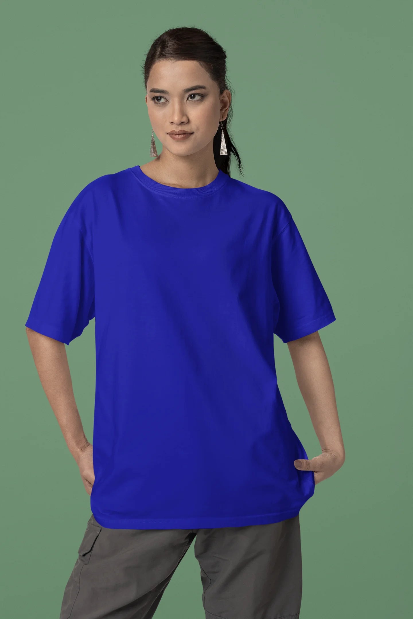 Front view of a female model wearing a royal blue oversized tee with a heron taking off under the moonlight.