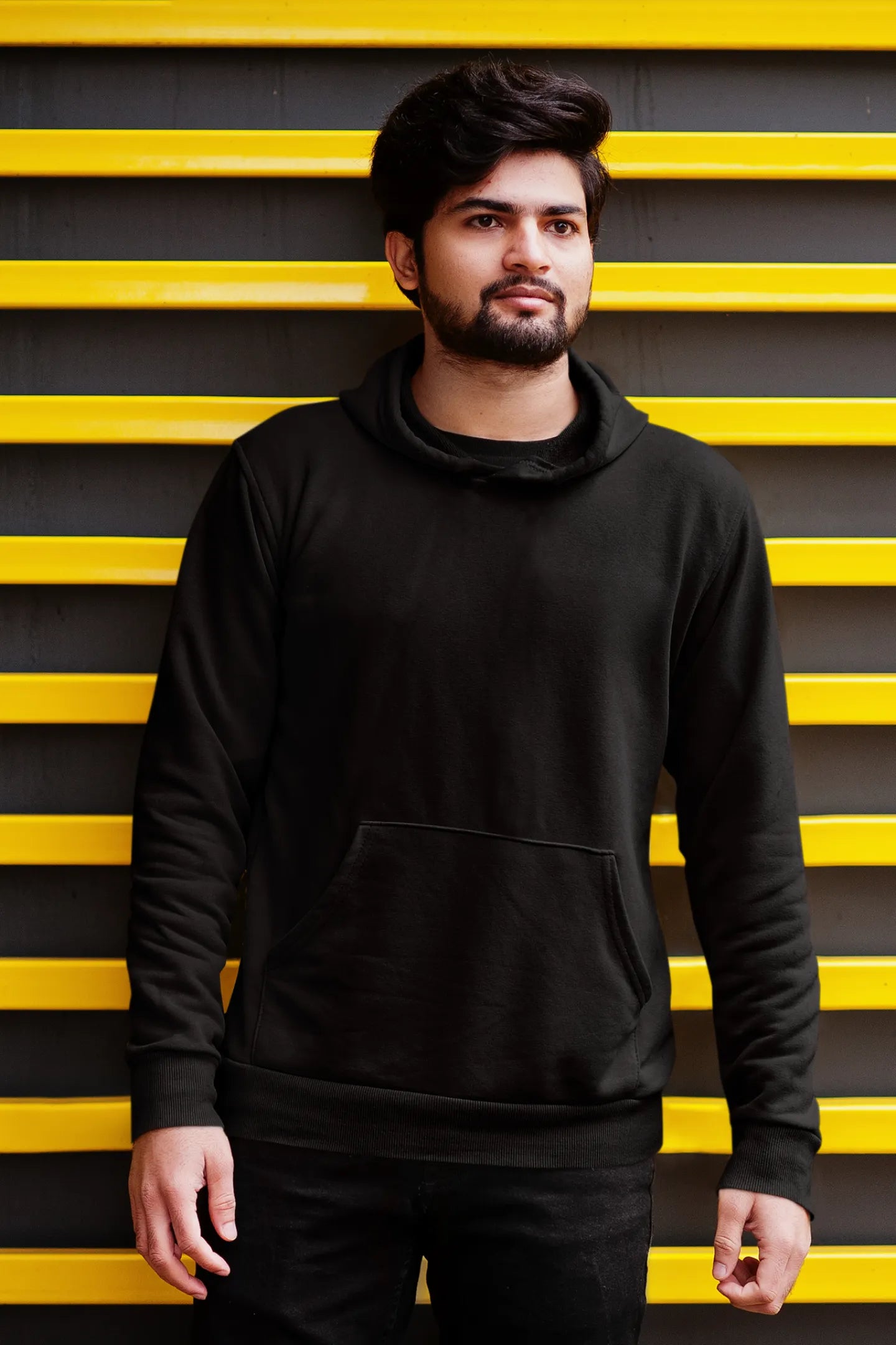 Third front view of a male model wearing a black hoodie featuring a Range Rover Defender design, exuding power and ruggedness.